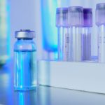 Frascos e tubos de ensaio com líquido azul em um laboratório sob iluminação fluorescente