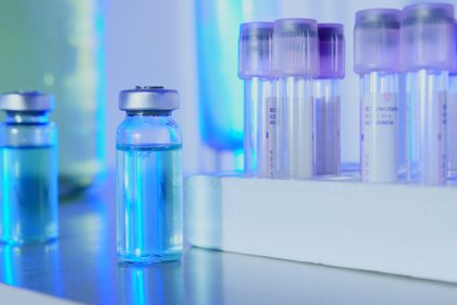Frascos e tubos de ensaio com líquido azul em um laboratório sob iluminação fluorescente