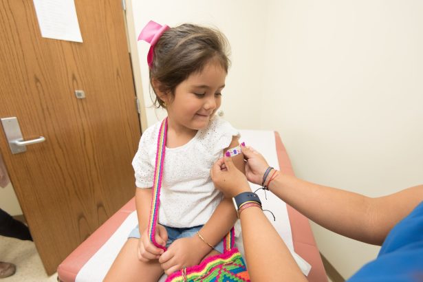 Menina recebe um curativo após ser vacinada em uma clínica.
