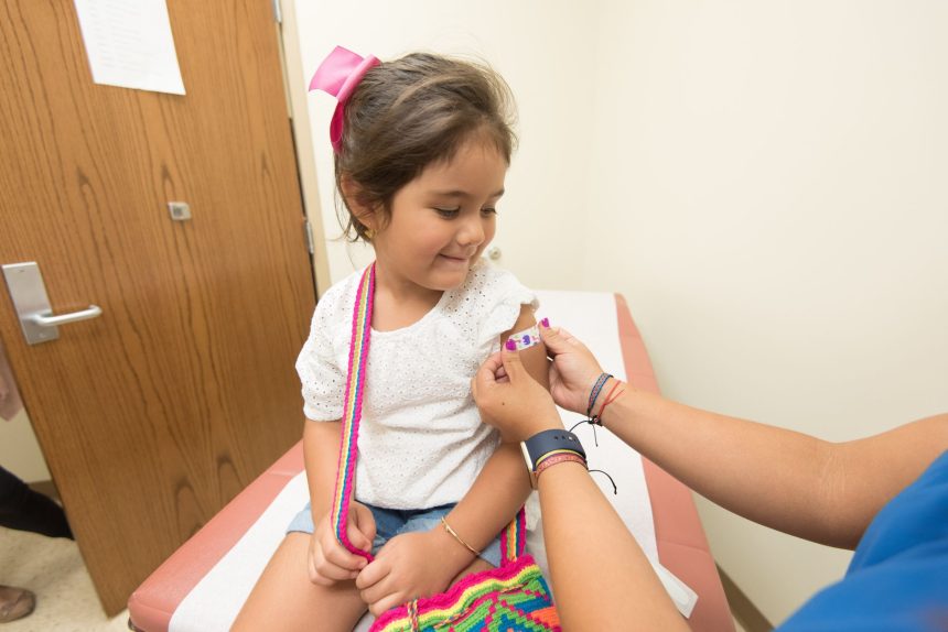 Menina recebe um curativo após ser vacinada em uma clínica.