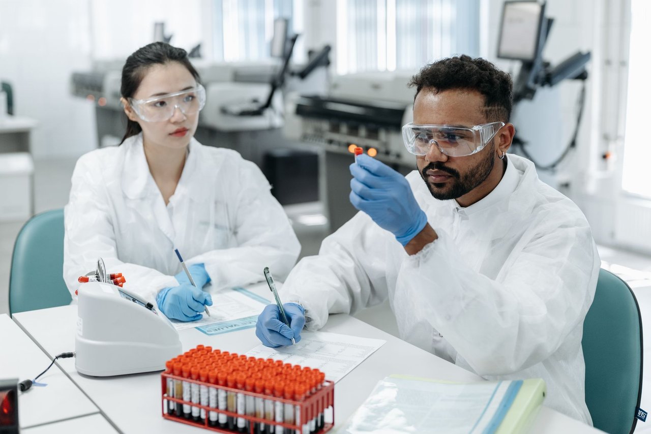 Dois cientistas analisam amostras e registram dados em um laboratório de pesquisa.