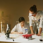 Dois pesquisadores trabalham com equipamentos e amostras em um laboratório de pesquisa.
